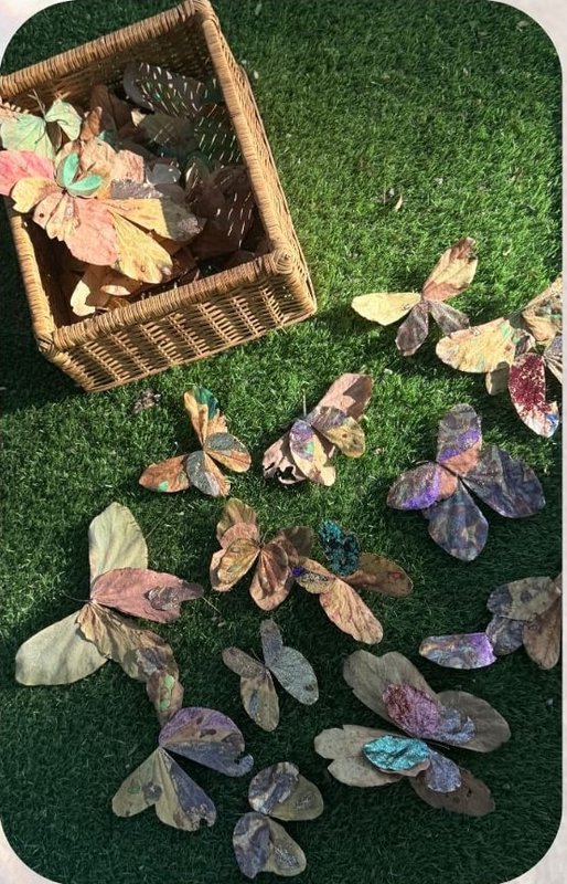 Decorated leaves gathered in a basket on grass.